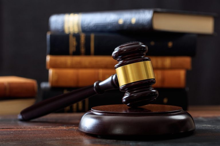 Law gavel on a wooden desk, law books background
